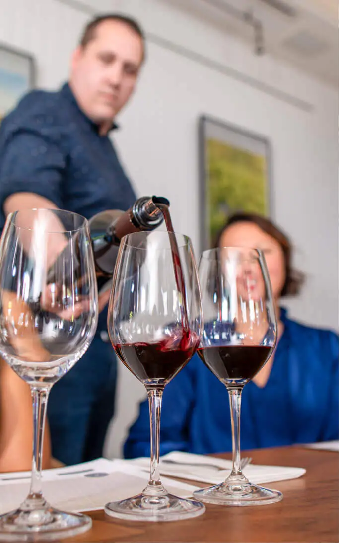 person pouring wine down a glass