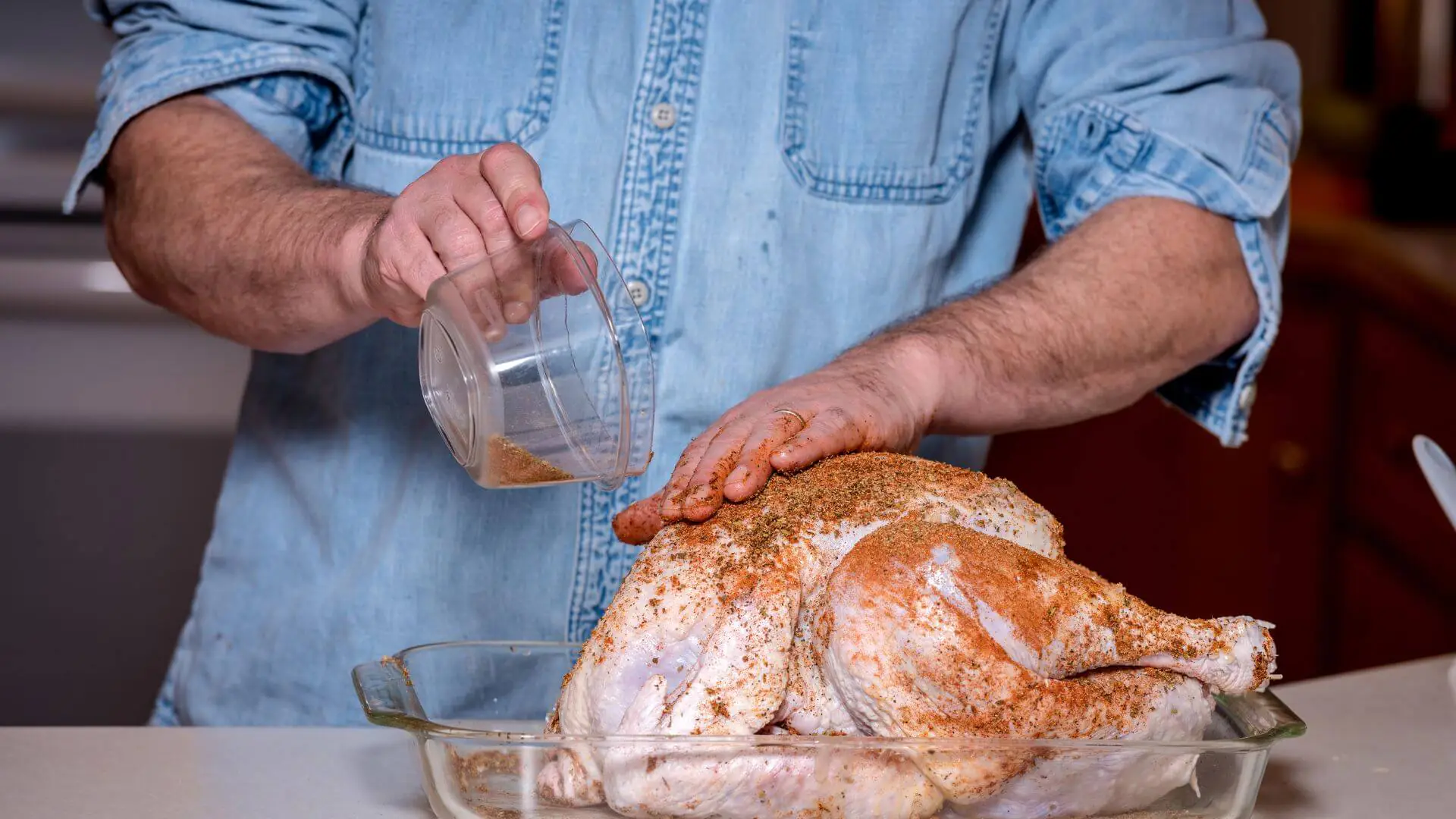 person putting spices over a uncocked turkey