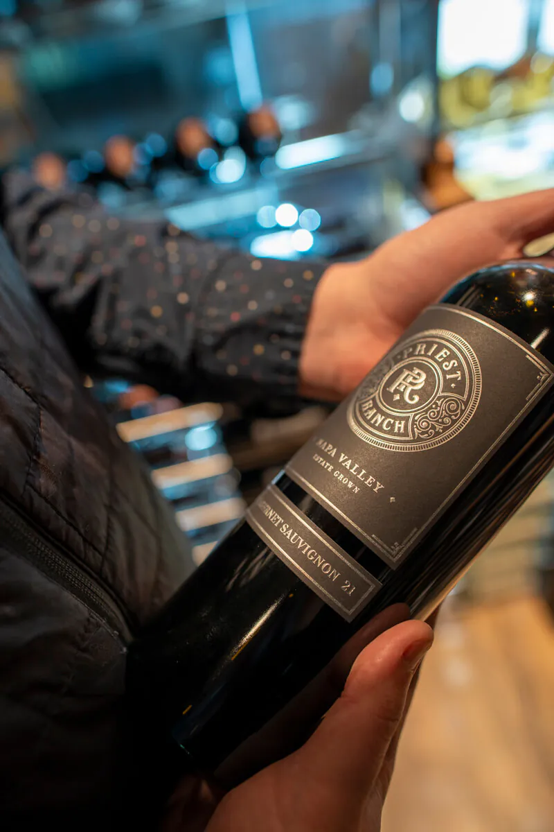 hands holding priest ranch wine bottle